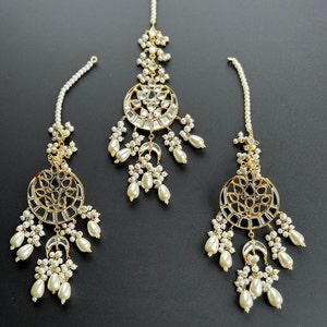 May include: A set of three gold-tone maang tikka headpieces with pearl and clear crystal embellishments. Each piece features a round, ornate design with a mirrored center.