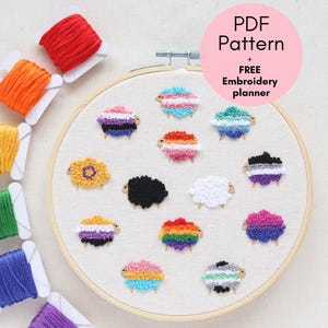 Puede incluir: Un bastidor de bordado con diseños de ovejas coloridas, cada una representando diferentes banderas del orgullo. El bastidor está rodeado de carretes de hilo de bordar colorido. El texto "PDF Pattern + FREE Embroidery planner" está en un círculo rosa.