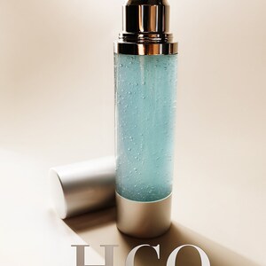 Puede incluir: Una botella de vidrio transparente con una tapa de bomba plateada y una tapa plateada. La botella est&aacute; llena de un l&iacute;quido azul claro y tiene peque&ntilde;as burbujas en todo. La botella est&aacute; etiquetada con "H2O PURE HYDRATION" y "Antiqueterra SKIN CARE".