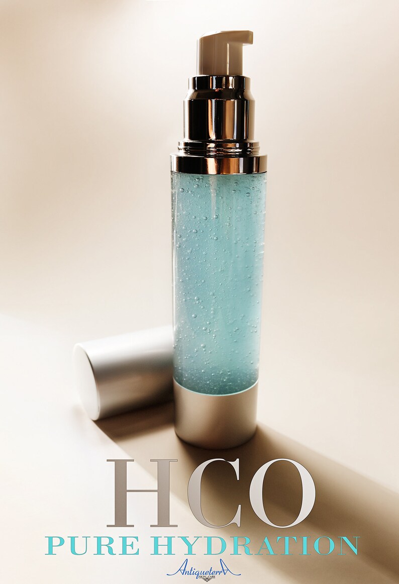 Puede incluir: Una botella de vidrio transparente con una tapa de bomba plateada y una tapa plateada. La botella est&aacute; llena de un l&iacute;quido azul claro y tiene peque&ntilde;as burbujas en todo. La botella est&aacute; etiquetada con "H2O PURE HYDRATION" y "Antiqueterra SKIN CARE".