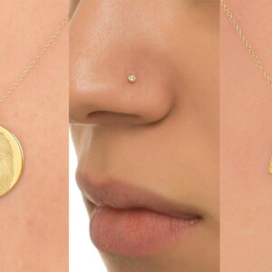 May include: A collection of gold jewelry featuring a heart-shaped ring, a necklace with an elephant pendant, a round pendant with a design, a nose ring, a heart-shaped pendant on a chain, and a ring with a row of small diamonds.