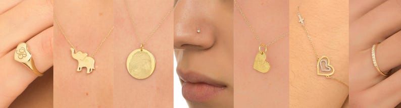 May include: A collection of gold jewelry featuring a heart-shaped ring, a necklace with an elephant pendant, a round pendant with a design, a nose ring, a heart-shaped pendant on a chain, and a ring with a row of small diamonds.