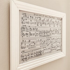 May include: A framed sheet of music with the title "Direct music N3 Auch и Маша Лазер" and musical notation. The music is written in black ink on white paper.