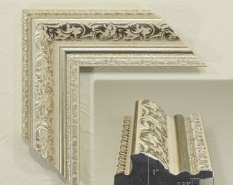 Puede incluir: Un marco de fotos plateado con un diseño ornamentado. El marco tiene 2,5 cm de ancho y 5,8 cm de alto. El marco está hecho de madera y tiene un acabado plateado.