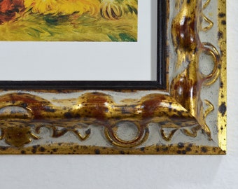 May include: A close-up of a gold-toned picture frame with a distressed, aged look. The frame has a raised, ornate design with a black inner edge.