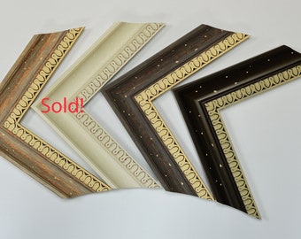 May include: Four ornate picture frames with gold accents and a decorative pattern. The frames are in different colors: brown, beige, and a light wood tone.