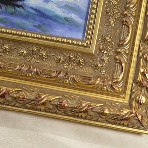May include: A gold-colored picture frame with ornate detailing. The frame has a raised edge and a textured surface. The frame is made of wood and has a dark brown finish.