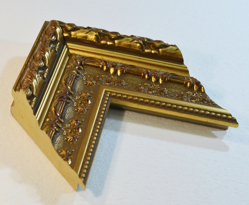 May include: A gold picture frame with ornate details and a beaded edge.