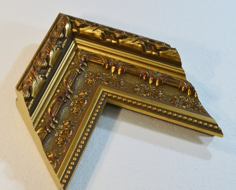 May include: A gold picture frame with ornate detailing and a beaded edge. The frame is made of wood and has a distressed finish.