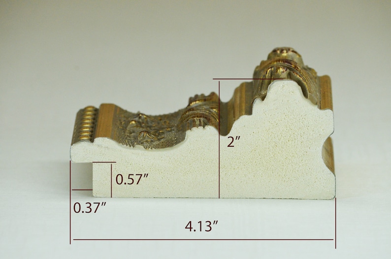 May include: A close-up of a white picture frame with gold accents. The frame is 2 inches tall, 4.13 inches wide, and 0.57 inches deep.