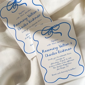 May include: A white wedding invitation with blue calligraphy. The invitation features a blue ribbon bow and the text "Together with their families Rosemary Valton & Charles Birkman Invite you to celebrate their marriage on Saturday, August 13, 2014 at four o'clock in the afternoon The Garden Properties San Diego, CA Dinner and dancing to follow!"