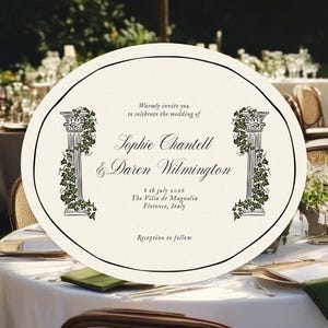 May include: An ivory wedding invitation with black text and decorative columns with green vines. The invitation is oval-shaped and sits on a white tablecloth, surrounded by wedding reception details.