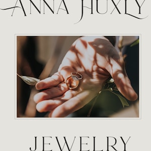 May include: Two gold wedding bands with a diamond ring on top, resting in the palm of a hand.