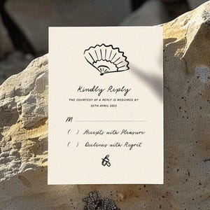 Puede incluir: Una tarjeta RSVP blanca con un dise&ntilde;o de abanico dibujado a mano en negro. El texto dice "Kindly Reply" e incluye la fecha "20th April 2023". La tarjeta tiene dos opciones para que los invitados elijan: "Accepts with Pleasure" y "Declines with Regret".