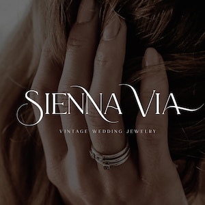 May include: A close-up of a hand wearing a stack of silver rings with a simple design. The text "SIENNA VIA VINTAGE WEDDING JEWELRY" is displayed below the hand.