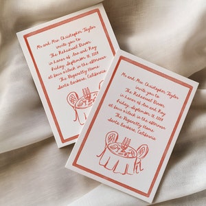 May include: A red and white invitation card with a red border. The card is for a rehearsal dinner in honor of Ann and Ray. The card features a hand-drawn illustration of a table setting with candles and a plate of food. The text on the card reads: "Mr and Mrs. Christopher Taylor invite you to The Rehearsal Dinner in honor of Ann and Ray Friday, September 18, 2014 at four o'clock in the afternoon The Pagaretty Home Santa Barbara, California"