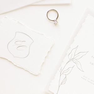 Puede incluir: Un conjunto de invitaciones de boda con un dise&ntilde;o simple y elegante. La invitaci&oacute;n presenta una ilustraci&oacute;n floral dibujada a mano y el texto "Elizabeth y Charles" con la fecha "21 de julio de 2020" y la ubicaci&oacute;n "Par&iacute;s, Francia". La tarjeta RSVP presenta un monograma con las iniciales "EC" en forma de escudo.