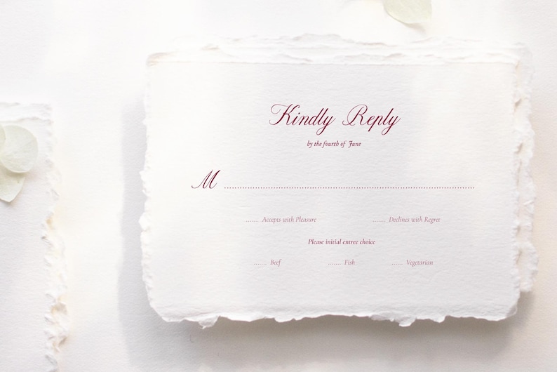 May include: A white invitation card with a deckled edge, featuring the words "Kindly Reply" in burgundy script. The card includes prompts for the recipient to respond, with options for meal choices.