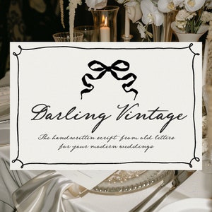 May include: A black and white sign with a handwritten script font that reads "Darling Vintage" and "The handwritten script from old letters for your modern weddings". The sign is decorated with a black ribbon bow.