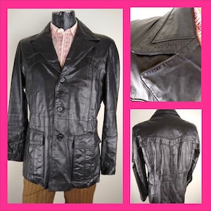 May include: A black leather jacket with a button-up front, two flap pockets, and a pointed collar. The jacket has a slightly textured surface.