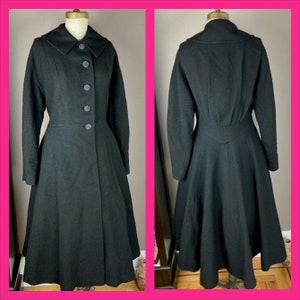 May include: A black wool coat with a flared skirt and a collar. The coat has a button closure and long sleeves.