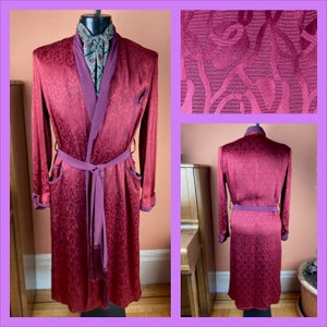 May include: A long, burgundy robe with a purple satin trim and a matching sash. The robe has a floral pattern and is made of a silky material.