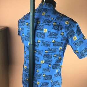May include: A blue short-sleeved shirt with a pattern of gold and black figures on a white background.