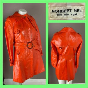 May include: A bright orange vinyl raincoat with a belt and a label that reads "Norbert Nel Paris Milan New York".