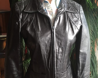 Peut inclure: Une veste en cuir noire avec une fermeture éclair et un col pointu. La veste a une silhouette ajustée et présente un détail de couture à l'avant et à l'arrière.