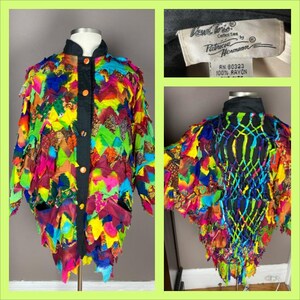 May include: A colorful, multi-patterned rayon jacket with a black button-up front. The jacket is made of many different pieces of fabric sewn together, creating a unique and eye-catching design. The label reads "Ventura Collection by Patricia Hermann, RN 80323, 100% Rayon."