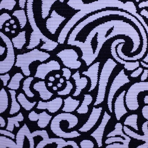 K&ouml;nnte beinhalten: Ein wei&szlig;er Stoff mit einem schwarzen Blumenmuster. Das Muster besteht aus Spiralen und Bl&auml;ttern.
