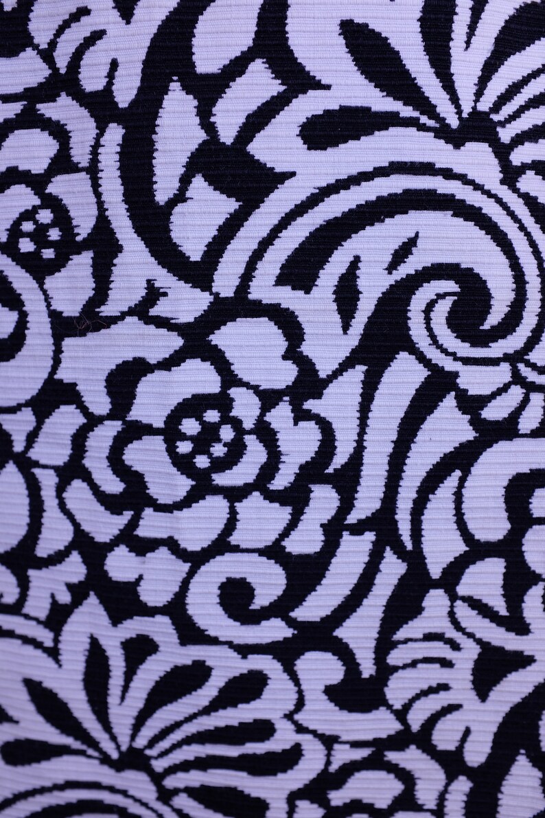 K&ouml;nnte beinhalten: Ein wei&szlig;er Stoff mit einem schwarzen Blumenmuster. Das Muster besteht aus Spiralen und Bl&auml;ttern.