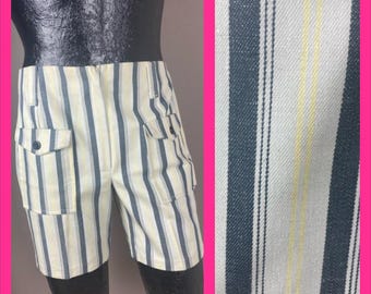 Peut inclure: Shorts vintage avec un motif à rayures verticales crème, bleu marine et jaune. Les shorts ont deux poches avant avec des boutons et deux poches latérales. Le tissu a un aspect texturé. La longueur est d'environ 40 cm.
