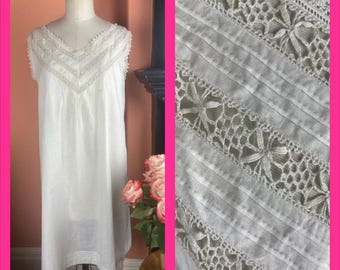 Puede incluir: Un camisón blanco sin mangas con escote en V, exhibido en un maniquí. El escote y los hombros están adornados con delicado encaje y abalorios. La tela del camisón parece ligera, con un primer plano detallado que muestra intrincados patrones de encaje.