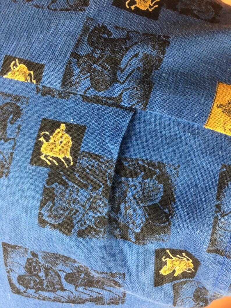 May include: Blue fabric with a repeating pattern of black and gold insects. The fabric has a textured weave.
