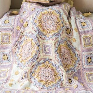 以下が含まれることがあります： 星と花の模様が施された、紫、ピンク、黄色の糸で編まれた毛布です。