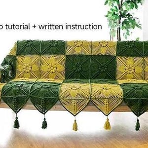 front view of sofa or couch with crochet sofa or green and ginger color couch cover on top, cover in quilt pattern, with victorial crochet pattern, couch cover having triangle edge decoration and tassel, in indoor background