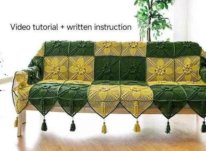 front view of sofa or couch with crochet sofa or green and ginger color couch cover on top, cover in quilt pattern, with victorial crochet pattern, couch cover having triangle edge decoration and tassel, in indoor background