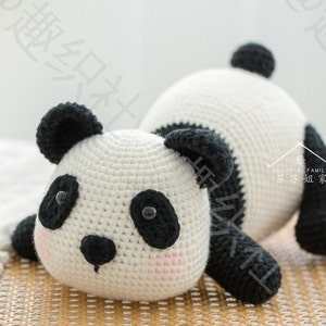 front view of cute panda stuffing panda amigurumi resting on bamboo meshed surface with tummy, panda's butt lifted in the air, with grey background