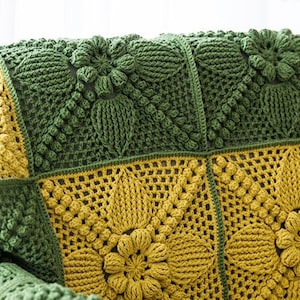 close up details of Victorian-Style floral granny square couch cover, patches in dark green and ginger yellow colors, joined with dark green crochet stitches, pop-corn stitches/symbols are frequently used