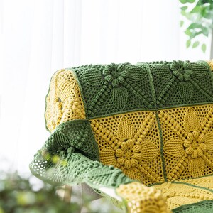 close up details of crochet sofa cover. cover made of green and ginger yellow, floral, victorian style granny square blocks, with a lot of pop corn motif, with indoor background