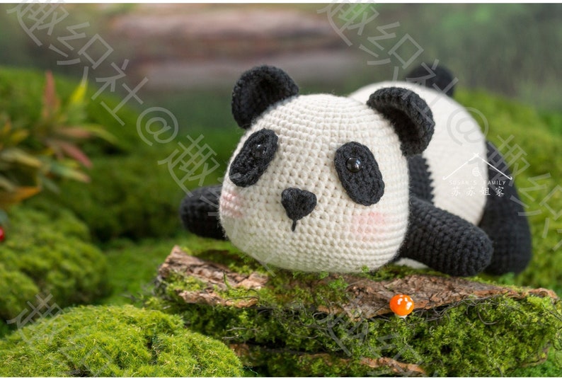 front view of big head cute panda lying on his chin, and tummy on rock, panda is in at right side of picture, in white and black, pale pink tint on cheeks, panda having big butt sticking high in air, arms and legs are short, with garden background