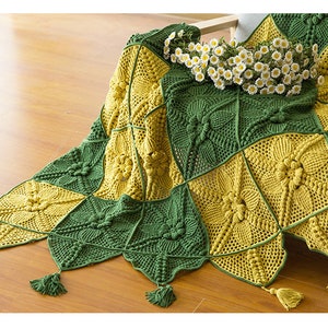 close up details of one corner of Victorian Style crochet couch cover, cover made with green and mustard color squar blocks, with triangle patchs and tassel as fringe, with floor background