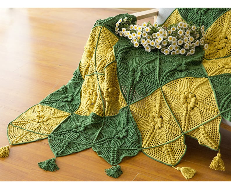 close up details of one corner of Victorian Style crochet couch cover, cover made with green and mustard color squar blocks, with triangle patchs and tassel as fringe, with floor background