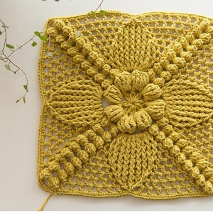 front view of ginger color Victorian-Style Floral crochet granny square patch, patch full of pop-corn stitches, flower center and flower petals, patch is big, on beige background