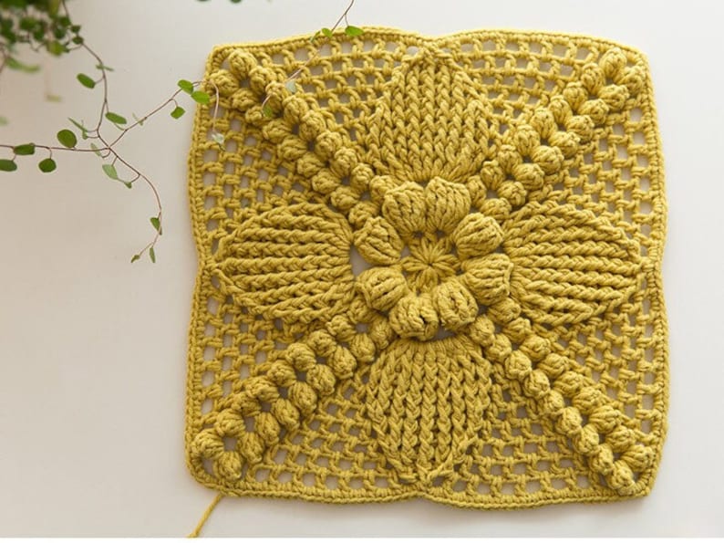 front view of ginger color Victorian-Style Floral crochet granny square patch, patch full of pop-corn stitches, flower center and flower petals, patch is big, on beige background