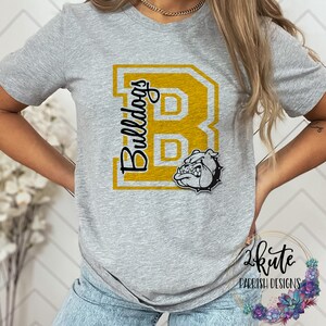 May include: Gray t-shirt with a gold "B" and the word "Bulldogs" printed on the front. A cartoon bulldog is inside the "B".