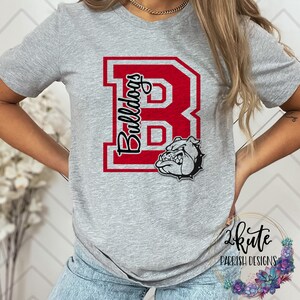 May include: Gray t-shirt with a red and white letter "B" with the word "Bulldogs" written vertically inside the letter. A cartoon bulldog head is below the letter.