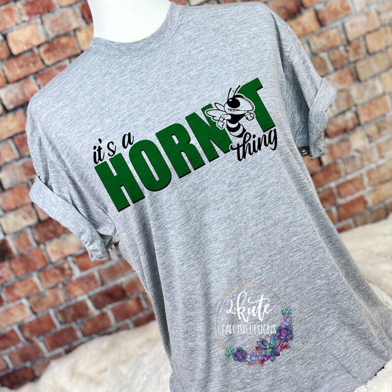 May include: A gray t-shirt with the text "it's a hornet thing" in green letters. A green hornet mascot is in the middle of the text.