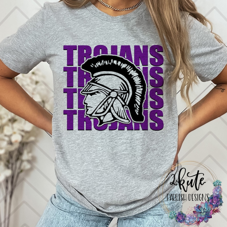 K&ouml;nnte beinhalten: Ein graues T-Shirt mit einer lilafarbenen Grafik eines trojanischen Kriegerhelms und dem Wort "Trojans", das viermal wiederholt wird.